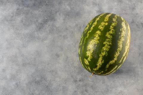 Green watermelon on a light gray background. Top view, copy space, healthy fo Stock Photos