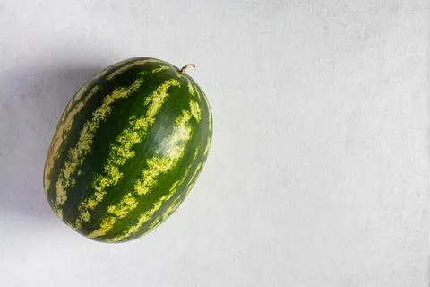 Green watermelon on a light gray background. Top view, copy space, healthy fo Stock Photos