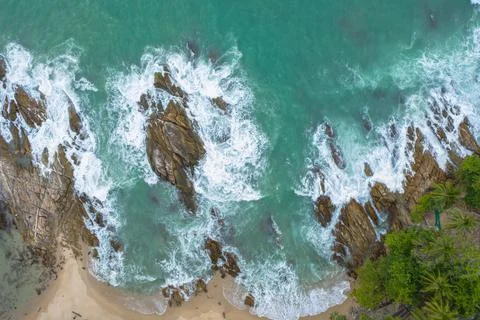 The green wave breaks the white bubble when it hits the rock. Stock Photos