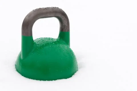 Green weight training kettlebell in the snow Stock Photos