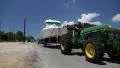Green wheeled tractor transporting the boat on a paved road HD Footage