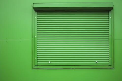 Green window shutter on green wall . Stock Photos