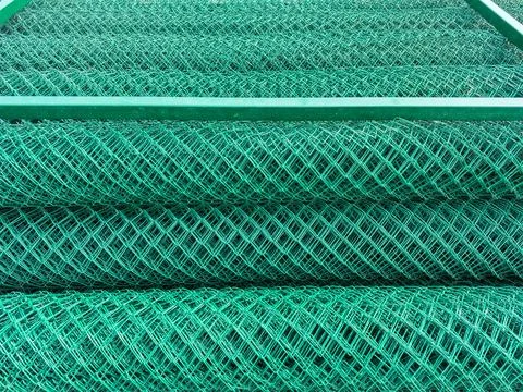 Green wire mesh rolls stacked at a construction site in the afternoon light.. Stock Photos
