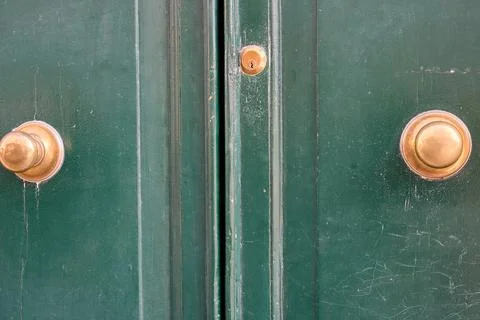 Green wooden door with brass knobs and keyhole close up. Fotos de archivo