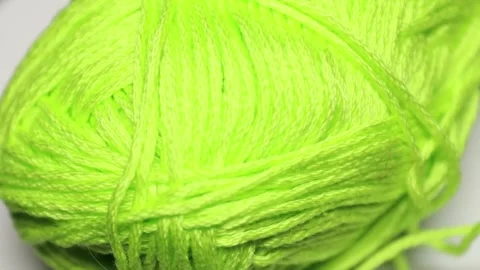 A green yarn ball sitting on a white surface, ready for knitting or crochet.. Видео 337048072