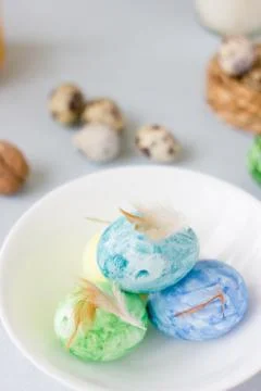 Green, yellow and blue easter eggs on ceramic bowl, bright and airy shot. Stock Photos