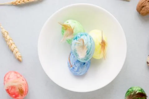 Green, yellow and blue easter eggs on ceramic bowl, bright and airy shot. Stock Photos