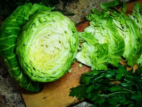 Green young cut half cabbage with parsley and dill on the wood. Closeup on wo Stock Photos
