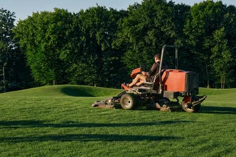 Greenkeeper. Golf course maintenance worker, cutting green grass Foto stock