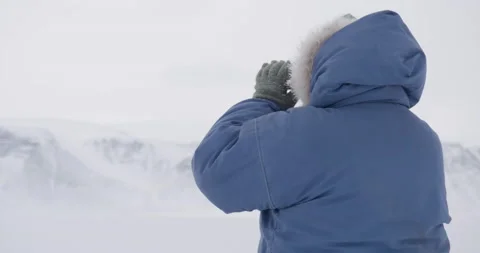 Greenland hunter searches through binoculars, shot from behind Stock Footage
