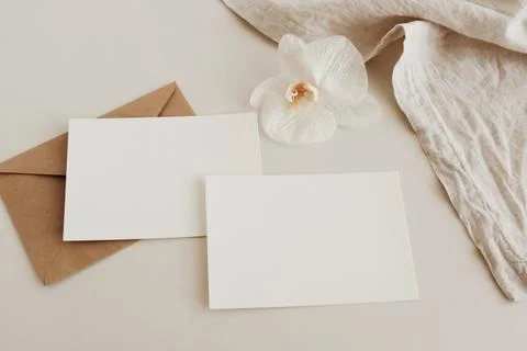 Greeting Cards mockup, empty white blanks, envelopes and orchid flower top view  Stock Photos