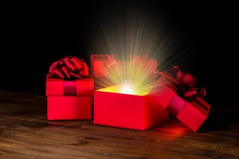 Greeting opened box with bow and miracle light on wooden background is isolat Stock Photos