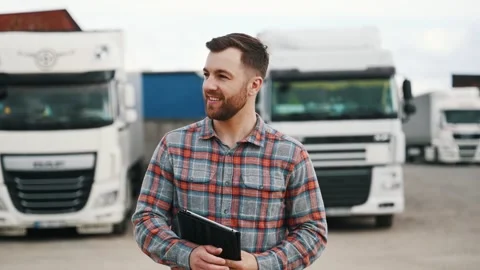 Greetings, hello hand gesture, smiling. Man is standing against trucks outdoors. Stock Footage 296174754