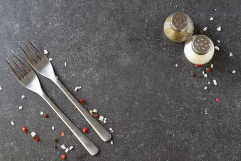 Grey abstract background with forks, salt and pepper shakers. Place for text. Foto stock