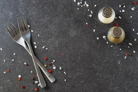 Grey abstract background with forks, salt and pepper shakers. Place for text. Stock Photos