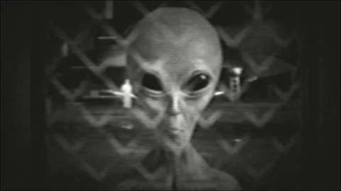 Grey alien extraterrestrial in dark black room, looking at viewer