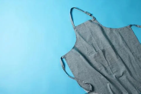 Grey apron with pattern on blue background, top view. Space for text Stock Photos
