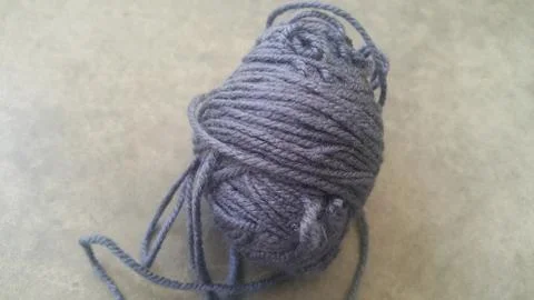 Grey ball of threads wool yarn for knitting on grey floor background Foto stock