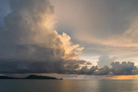 Grey blue sky with a big cloud coating with orange sunset light and sea Stock Photos