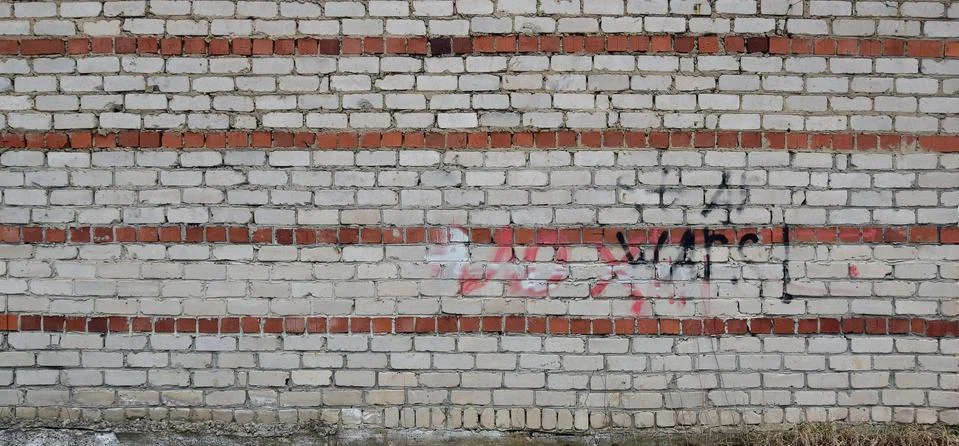 Grey brick wall with traces of destruction and dirty texture Stock Photos