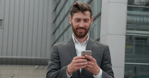 Grey Building on the Background of Young dark-Haired Business Man. He is Reading Stock Footage 125153740
