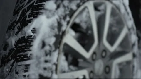 Grey car big wheels spin and spit up heavy wet snow as unknown driver tries to Stock Footage 234699989
