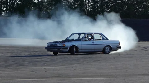 Grey car drifting around corner in slow motion with smoke trail. Stock Footage 59746808