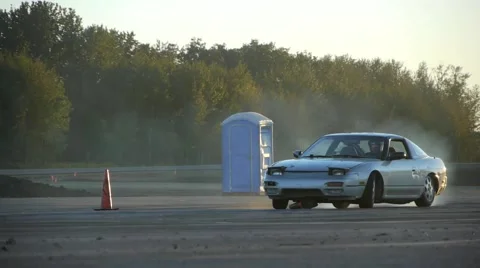 Grey car drifts around corner with pylon stuck underneath it. Stock-Footage 59761979