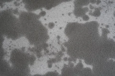 A grey cement plaster wall with dark abstract spots as a background. Stock Photos