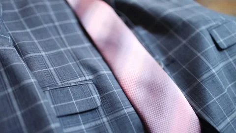 A grey checked suit with a pink tie on a hanger. 스톡 동영상 131893096