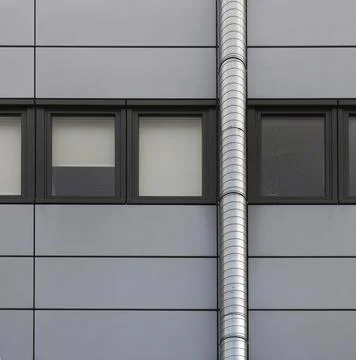 Grey cladding panels on an industrial building with a row of back window frames Stock Photos