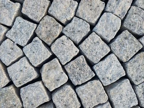 Grey cobblestone pavement composed of tightly arranged square blocks with r.. Stock Photos