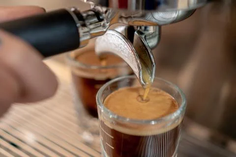 Grey coffee machine with two cups filled with coffee on a metal grid in close Stock Photos