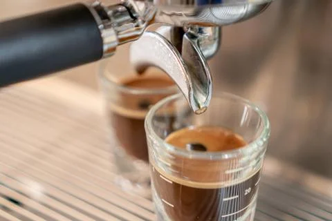 Grey coffee machine with two cups filled with coffee on a metal grid in close Stock Photos