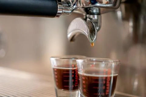 Grey coffee machine with two cups filled with coffee on a metal grid in close Stock Photos