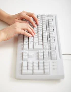 Grey computer keyboard and hands working on it Stock Photos