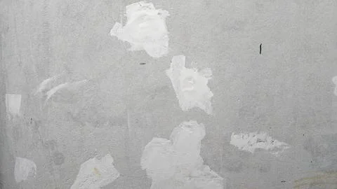 Grey concrete wall texture with weathered plaster patches and rough industrial Stock Photos