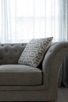 Grey couch with a patterned throw pillow Stock Photos