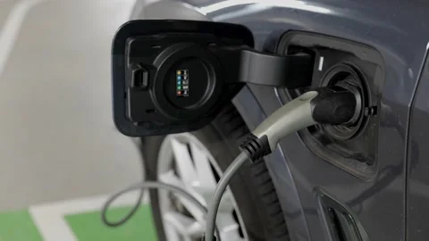 Grey electric car with power plug charging in garage Видео 220549624