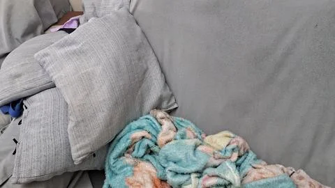 Grey fabric couch featuring cozy soft cushions and warm patterned throw Stock Photos