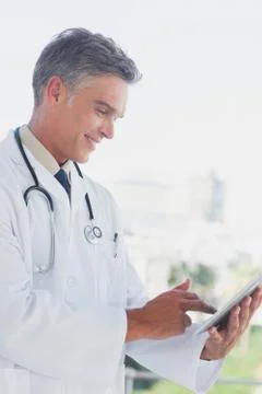 Grey haired doctor using digital tablet Stock Photos