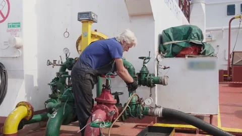 Grey haired donkeyman in blue t-shirt controls fuel pumping Stock Footage 148389111