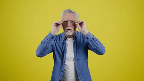 Grey-haired elderly man squints and takes off glasses Stock Footage 230481397