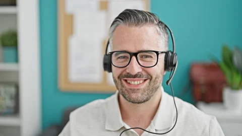 Grey-haired man business worker wearing headphones at the office Video stock 246992588