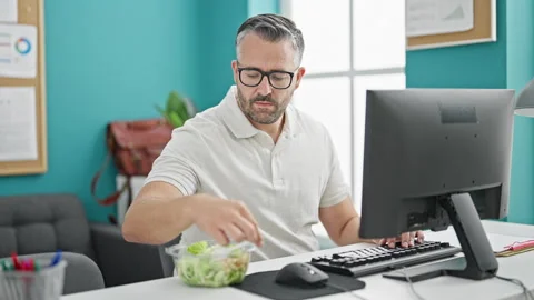 Grey-haired man business worker eating salad working at the office Stock Footage 246992605