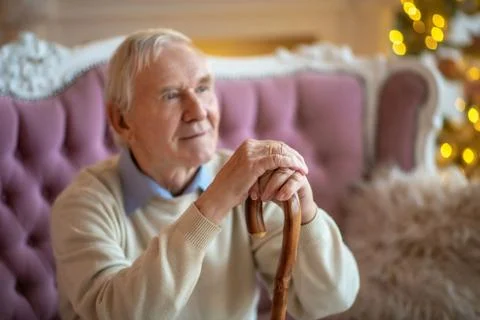 Grey-haired man sitting on the sofa and looking aside Stock-Fotos