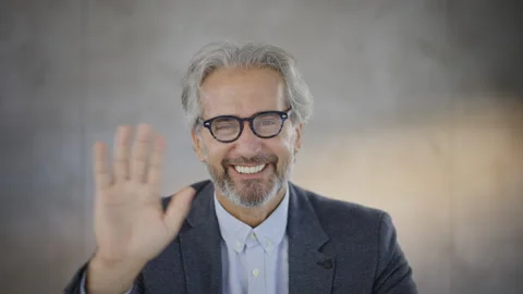 Grey haired man waving to camera. End of video call. Head and shoulders shot. Stock Footage 164462451