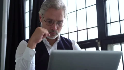 Grey-haired man working on a laptop. Serious mature man in elegant suit typing Vídeo Stock 140642639