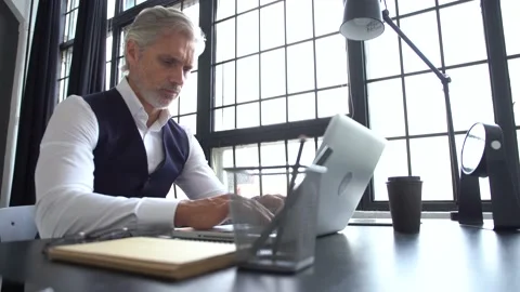Grey-haired man working on a laptop. Serious mature man in elegant suit typing Stock Footage 140642764