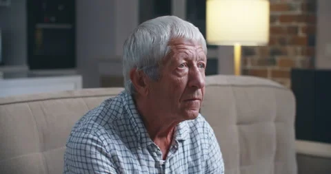 Grey haired old man sit on couch in living room alone, lost in sad pessimistic Stock Footage 135607310